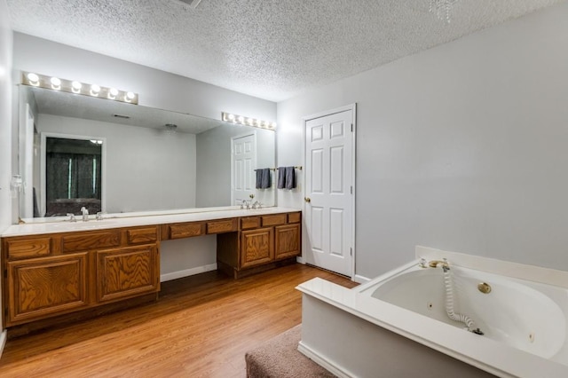 238 Browning Ln, Grand Prairie, TX 75052 - full bathroom with double vanity, wood finished floors, a whirlpool tub, a textured ceiling, and baseboards