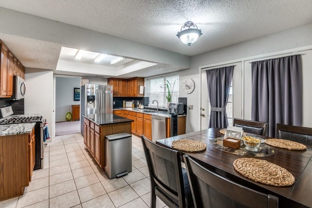 238 Browning Ln, Grand Prairie, TX 75052 - kitchen with appliances with stainless steel finishes, a sink, brown cabinetry, a textured ceiling, and light tile patterned floors