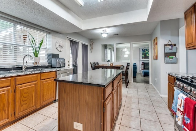 238 Browning Ln, Grand Prairie, TX 75052 - kitchen featuring a textured ceiling, stainless steel appliances, a sink, a center island, and brown cabinets