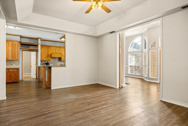 2809 Rock Church Hwy, Tolar, TX 76476 - unfurnished living room featuring a ceiling fan, a tray ceiling, dark wood-type flooring, baseboards, and a sink