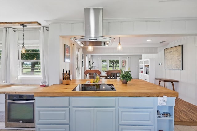 177 Graben Ln, Rhome, TX 76078 - kitchen with black electric stovetop, stainless steel oven, butcher block countertops, island exhaust hood, and decorative light fixtures
