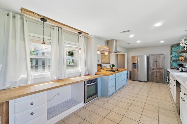 177 Graben Ln, Rhome, TX 76078 - kitchen featuring wood counters, appliances with stainless steel finishes, island range hood, light tile patterned floors, and blue cabinetry