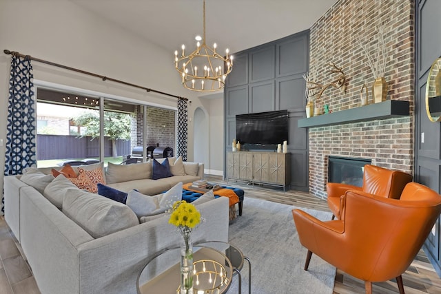 4350 Bristleleaf Ln, Prosper, TX 75078 - living area featuring a chandelier, wood finished floors, a brick fireplace, and arched walkways