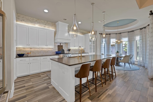 4350 Bristleleaf Ln, Prosper, TX 75078 - kitchen with premium range hood, dark countertops, a sink, light wood-style floors, and backsplash