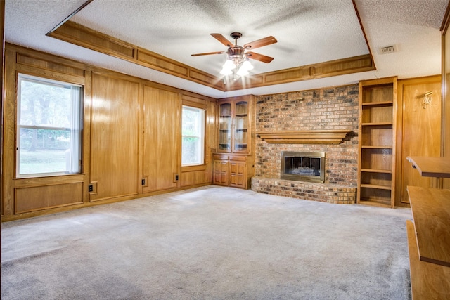 4465 Northern Dancer Dr, Burleson, TX 76028 - unfurnished living room featuring a tray ceiling, a textured ceiling, ceiling fan, a fireplace, and carpet