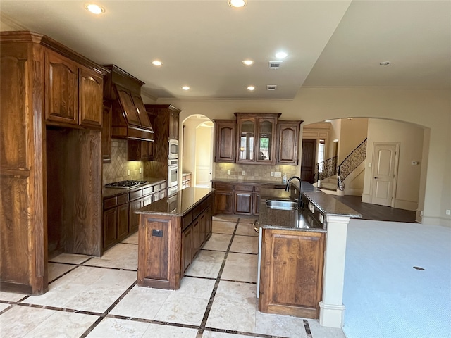6916 Cannon Falls Dr, Plano, TX 75024 - kitchen featuring an island with sink, appliances with stainless steel finishes, arched walkways, a sink, and recessed lighting