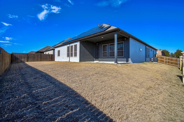 2213 Windy Hill Ln, Waxahachie, TX 75167 - rear view of house with solar panels, central AC, a fenced backyard, and brick siding