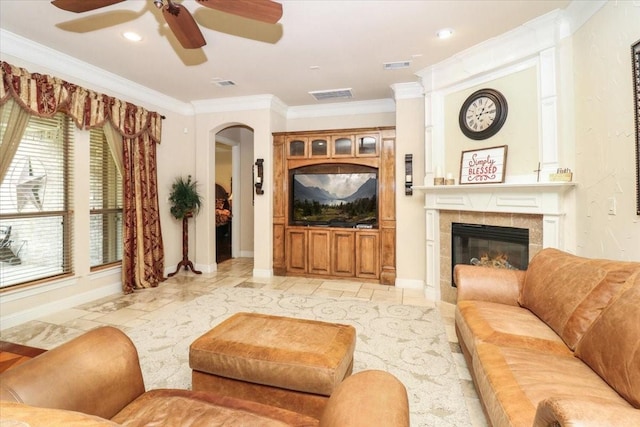 2221 Southern Oaks Dr, Cedar Hill, TX 75104 - living room with ornamental molding, a ceiling fan, a tiled fireplace, baseboards, and arched walkways