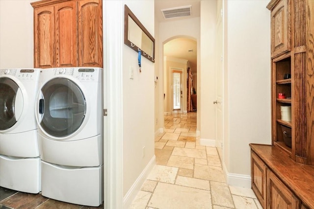2221 Southern Oaks Dr, Cedar Hill, TX 75104 - laundry area with cabinet space, independent washer and dryer, arched walkways, stone tile flooring, and baseboards