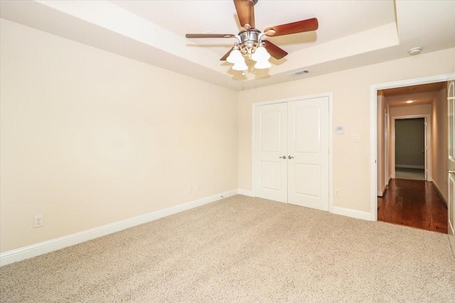 2221 Southern Oaks Dr, Cedar Hill, TX 75104 - unfurnished bedroom with a tray ceiling, carpet flooring, a closet, baseboards, and a ceiling fan