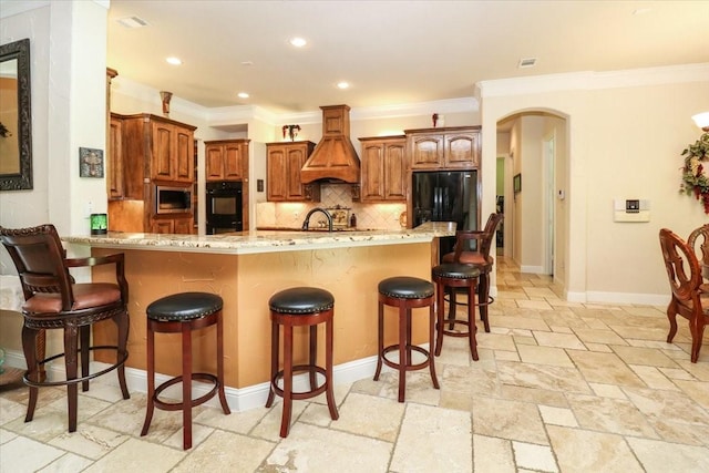 2221 Southern Oaks Dr, Cedar Hill, TX 75104 - kitchen with black appliances, stone tile floors, arched walkways, custom exhaust hood, and backsplash