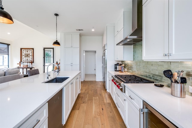 5270 Town And Country Unit 326, Frisco, TX 75034 - kitchen with wall chimney exhaust hood, a sink, stainless steel appliances, beverage cooler, and decorative backsplash