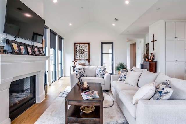 5270 Town And Country Unit 326, Frisco, TX 75034 - living area featuring a glass covered fireplace, vaulted ceiling, light wood finished floors, and recessed lighting