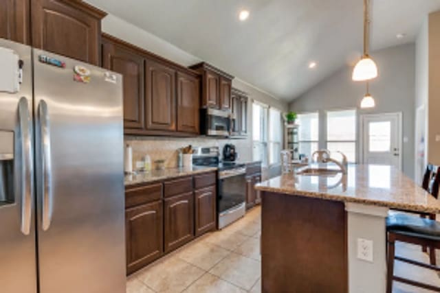 11520 Starlight Ranch Trl, Fort Worth, TX 76052 - kitchen with stainless steel appliances, a kitchen breakfast bar, a sink, an island with sink, and vaulted ceiling