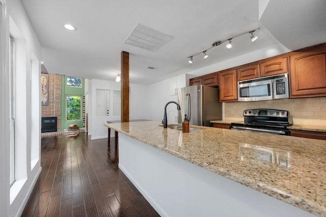 3227 Elizabeth St, Dallas, TX 75204 - kitchen featuring stainless steel appliances, light stone counters, tasteful backsplash, brown cabinets, and recessed lighting