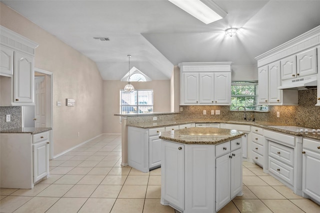6705 Rolling Hills Dr, North Richland Hills, TX 76182 - kitchen with a sink, a peninsula, under cabinet range hood, light tile patterned floors, and vaulted ceiling