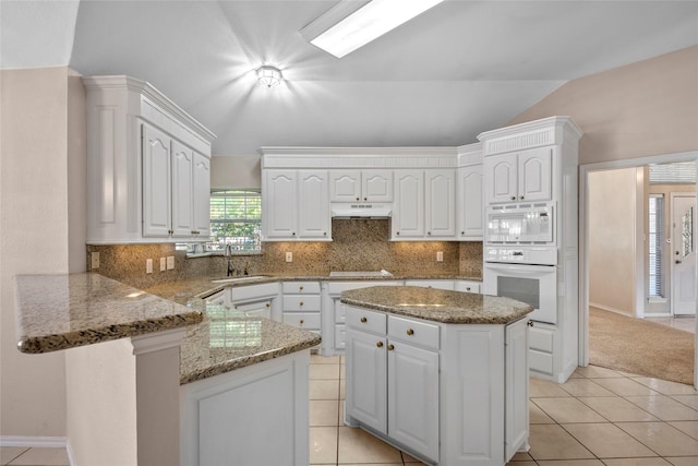 6705 Rolling Hills Dr, North Richland Hills, TX 76182 - kitchen with white appliances, a peninsula, white cabinetry, a sink, and under cabinet range hood