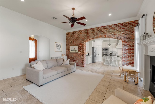 9961 Loveland Ct, Shreveport, LA 71106 - living room with arched walkways, a ceiling fan, ornamental molding, a fireplace, and brick wall