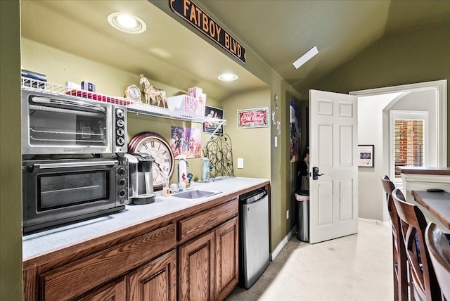 1304 Salsbury Cir, Murphy, TX 75094 - kitchen with dishwasher, brown cabinets, vaulted ceiling, light colored carpet, and light countertops