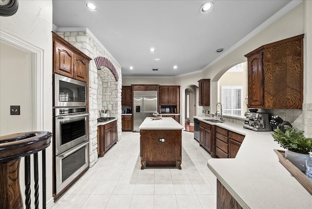 1304 Salsbury Cir, Murphy, TX 75094 - kitchen featuring built in appliances, light countertops, arched walkways, a center island, and ornamental molding