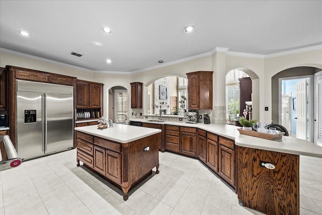 1304 Salsbury Cir, Murphy, TX 75094 - kitchen featuring stainless steel built in refrigerator, light countertops, a peninsula, arched walkways, and ornamental molding