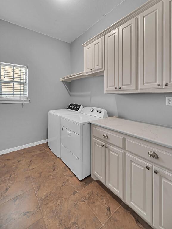 804 Heritage Pkwy, Axtell, TX 76624 - laundry area featuring cabinet space, washing machine and clothes dryer, and baseboards