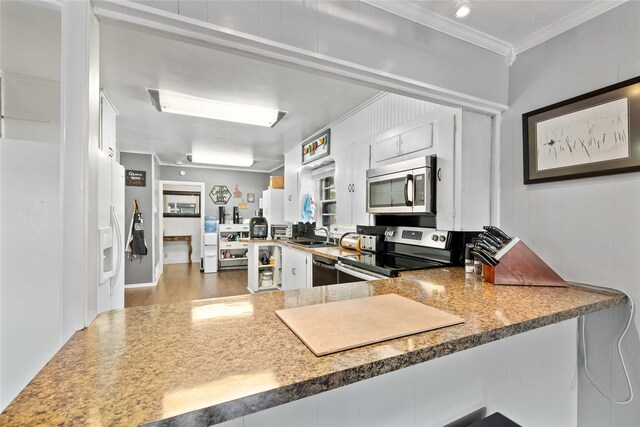 2202 Belmeade Ave, Brownwood, TX 76801 - kitchen featuring appliances with stainless steel finishes, crown molding, a peninsula, wood finished floors, and a sink