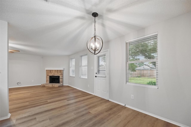 2922 Sheridan Ln, Wylie, TX 75098 - unfurnished living room featuring wood finished floors, a fireplace, a chandelier, a textured ceiling, and baseboards