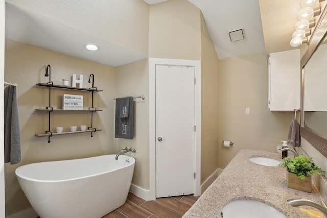 9 Chimney Rock Dr, Trophy Club, TX 76262 - full bathroom with a freestanding tub, double vanity, wood finished floors, baseboards, and lofted ceiling