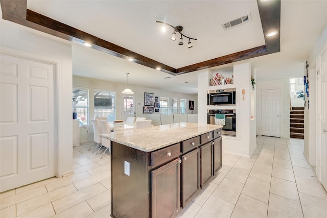 225 Redhead Dr, Little Elm, TX 75068 - kitchen with stainless steel oven, light tile patterned floors, dark brown cabinets, a center island, and light stone countertops
