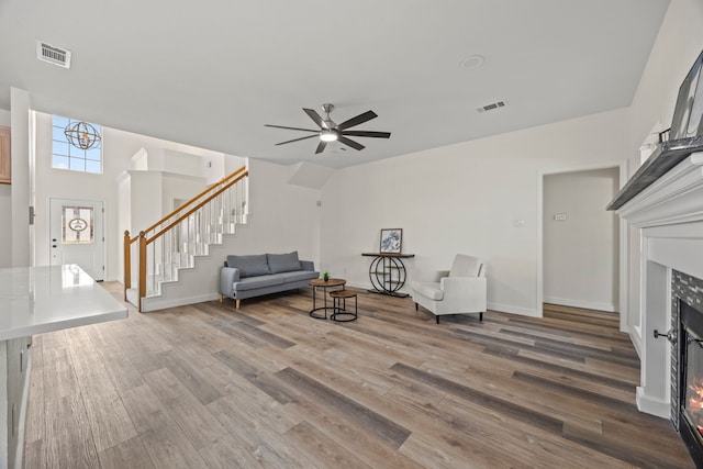 8901 Elbe Trl, Fort Worth, TX 76118 - sitting room featuring stairway, a warm lit fireplace, wood finished floors, a ceiling fan, and baseboards