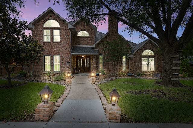 2304 Colleen Ct, Carrollton, TX 75007 - traditional-style house with a chimney, a lawn, brick siding, and roof with shingles