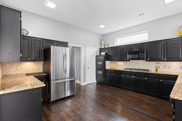2304 Colleen Ct, Carrollton, TX 75007 - kitchen with black appliances, dark wood-style flooring, dark cabinets, tasteful backsplash, and light stone countertops
