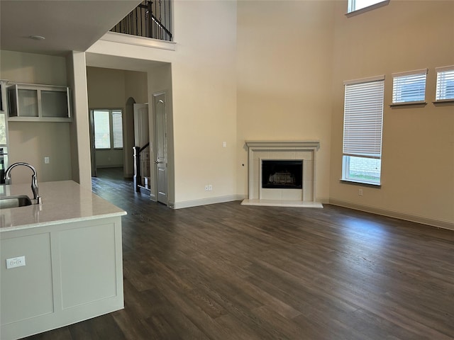 1308 Carlet Dr, Little Elm, TX 75068 - unfurnished living room featuring a high ceiling, a sink, dark wood-style flooring, a fireplace, and baseboards