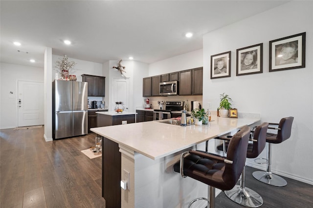 2212 Rosemary Way, Anna, TX 75409 - kitchen featuring appliances with stainless steel finishes, a sink, dark brown cabinetry, dark wood-type flooring, and a kitchen breakfast bar
