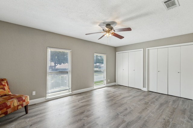 3233 Princess St, Bedford, TX 76021 - bedroom with wood finished floors, multiple closets, a textured ceiling, baseboards, and a ceiling fan