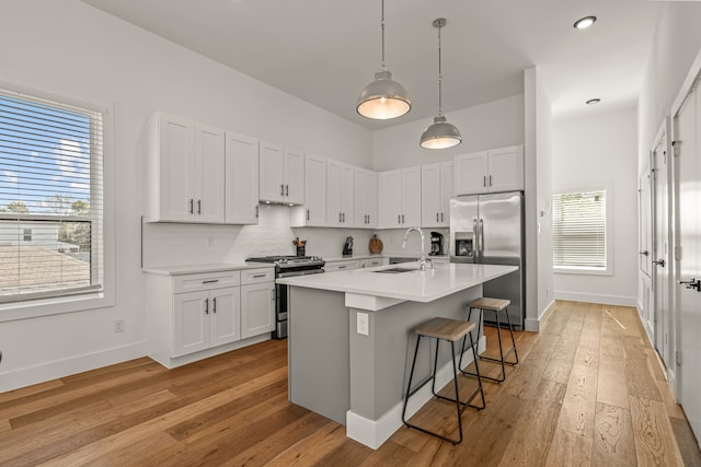 908 Muncie Ave, Dallas, TX 75212 - kitchen with stainless steel appliances, a sink, light countertops, a kitchen bar, and light wood-type flooring