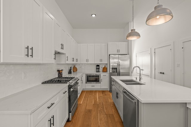 908 Muncie Ave, Dallas, TX 75212 - kitchen featuring a sink, appliances with stainless steel finishes, decorative backsplash, light wood-style flooring, and an island with sink