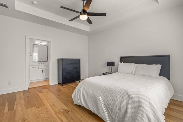 908 Muncie Ave, Dallas, TX 75212 - bedroom featuring a raised ceiling, light wood-style floors, a sink, baseboards, and ensuite bath