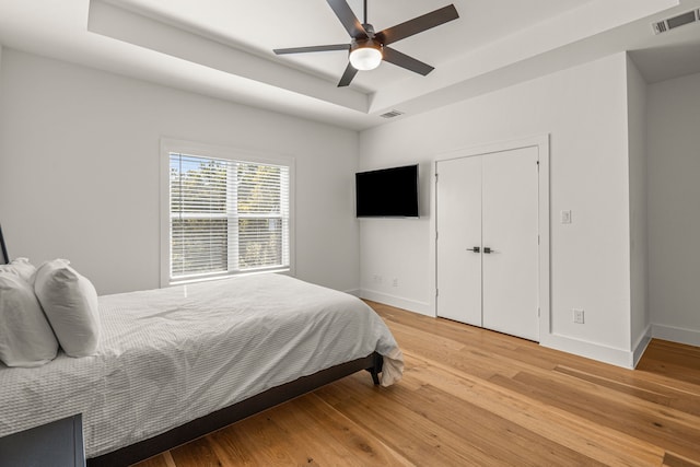908 Muncie Ave, Dallas, TX 75212 - bedroom featuring a tray ceiling, light wood-type flooring, baseboards, and a ceiling fan