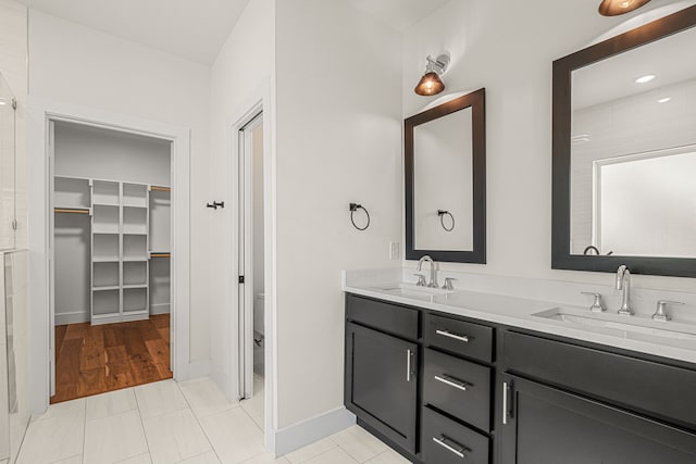 920 Muncie Ave, Dallas, TX 75212 - bathroom with double vanity, a walk in closet, tiled shower, toilet, and baseboards