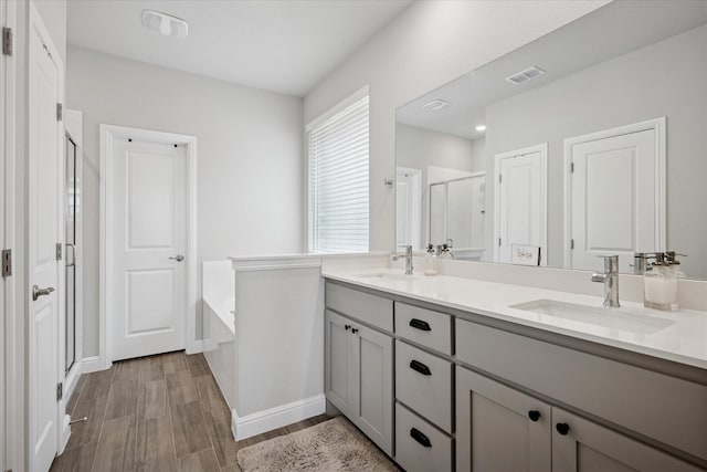 517 Big Horn Pass, Denton, TX 76210 - full bath featuring a stall shower, double vanity, a garden tub, wood finished floors, and baseboards