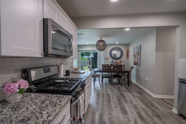 1306 S Oak Cliff Blvd, Dallas, TX 75208 - kitchen featuring stainless steel appliances, white cabinetry, light stone counters, light wood-style floors, and backsplash