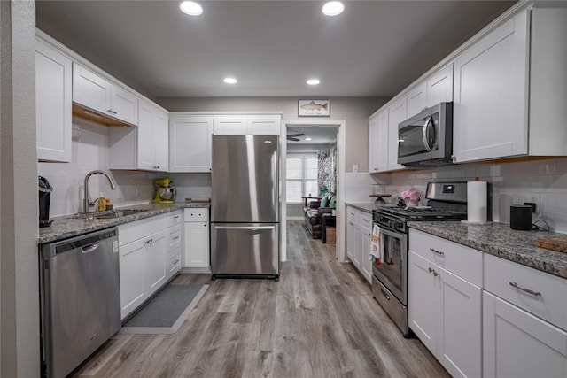 1306 S Oak Cliff Blvd, Dallas, TX 75208 - kitchen with appliances with stainless steel finishes, a sink, light wood-style floors, white cabinetry, and recessed lighting