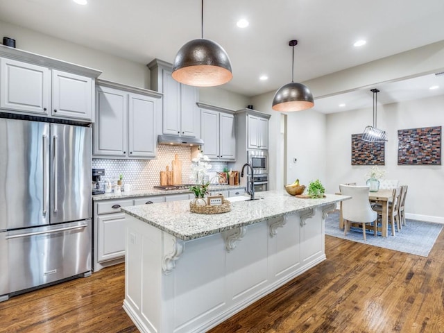5717 Dr Kenneth Cooper Dr, Mckinney, TX 75070 - kitchen with appliances with stainless steel finishes, a sink, dark wood finished floors, a breakfast bar area, and recessed lighting