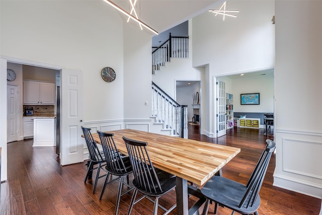 7905 Cherry Creek Dr, Plano, TX 75025 - dining room featuring a high ceiling, stairs, dark wood finished floors, a chandelier, and a decorative wall
