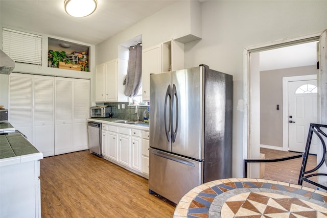 6980 Prather Rd, Springtown, TX 76082 - kitchen with appliances with stainless steel finishes, light wood-style flooring, a sink, and white cabinetry