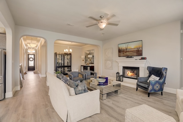 1305 Xeraco Dr, Little Elm, TX 75068 - living area with arched walkways, a glass covered fireplace, light wood finished floors, ceiling fan, and a chandelier