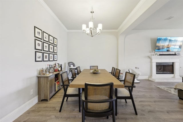 1305 Xeraco Dr, Little Elm, TX 75068 - dining area featuring a chandelier, crown molding, light wood finished floors, a fireplace with raised hearth, and baseboards