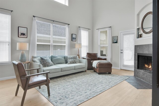 1356 Portsmouth Dr, Providence Village, TX 76227 - living room with light wood-type flooring, a tile fireplace, baseboards, healthy amount of natural light, and a high ceiling